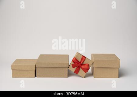 Cardboard box tied with red ribbon among craft boxes on white background, copy space Stock Photo