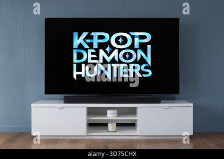 A widescreen OLED television showing the logo of the Netflix TV series K-Pop Demon Hunters seen in a contemporary living room. Stock Photo