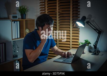 happy young man using wireless earbuds to listening music and laptop at a night Stock Photo