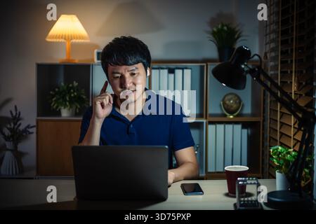 happy young man using wireless earbuds to listening music and laptop at a night Stock Photo