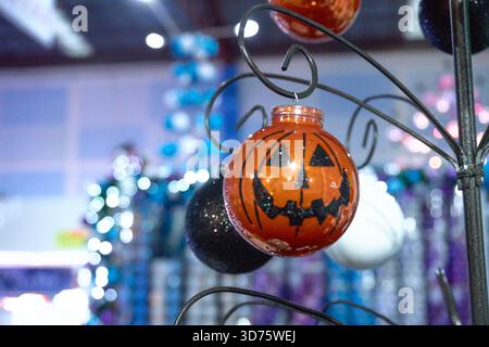 A hanging ornament with a pumpkin face and a pumpkin stem. The pumpkin is orange and black. Mexico, Puebla, Chignahuapan, decorative Christmas balls w Stock Photo