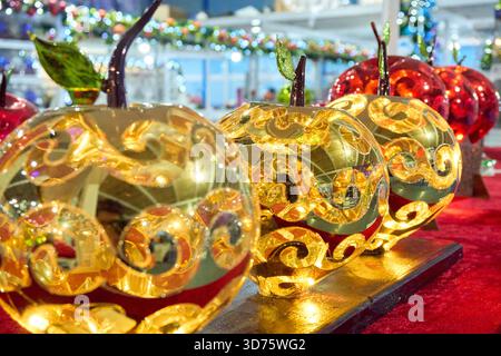 Three shiny apples with a leaf on top are displayed on a table. The apples are gold and red, and they are lit up. Mexico, Puebla, Chignahuapan, decora Stock Photo