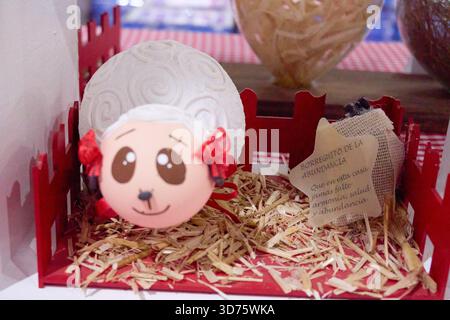 A stuffed animal with a red and white face sits in a red and white basket. The basket is on a table. Mexico, Puebla, Chignahuapan, decorative Christma Stock Photo