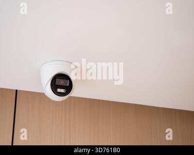 Indoor security camera mounted on ceiling in modern building, representing surveillance system, safety monitoring, CCTV installation, and smart securi Stock Photo
