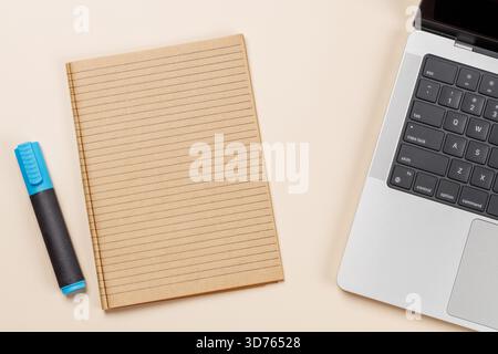 Blank notepad, laptop and stationery on beige workspace, top view with copy space, minimal office background Stock Photo