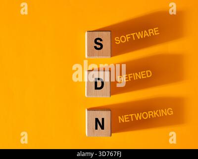Software Defined Networking concept is represented by wooden cubes casting shadows on an orange background Stock Photo