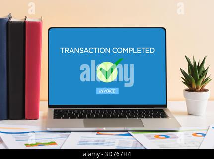 Laptop showing transaction completed message with check mark and invoice button on the screen, successful online payment concept Stock Photo