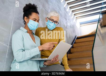 Busy business people, programmers software developer engineer working on computer in office in masks Stock Photo