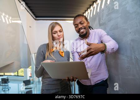Team collaboration and digital transformation with colleagues sharing ideas at a laptop in office Stock Photo