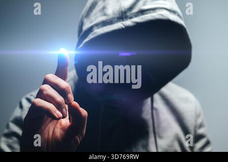 Faceless hooded man touching virtual screen, concept of network security, hacking, data protection, and cyber technology. Selective focus. Stock Photo