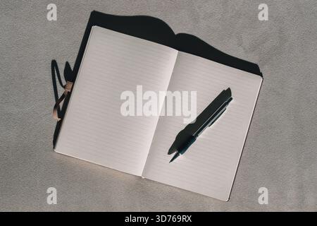 Open notebook with empty white pages and a pencil viewed from above, clean and simple stationary scene. Directly above. Stock Photo