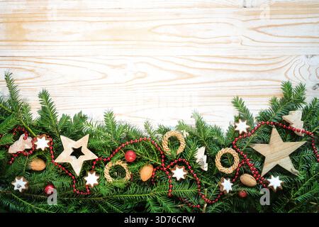 Christmas holiday background with fir tree branches, wooden stars, straw rings, walnuts, cookies and more decoration as bottom border on light rustic Stock Photo