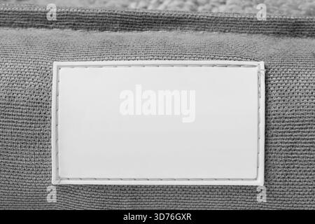 Blank white rubber patch stitched on grey fabric background closeup Stock Photo