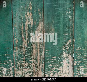 An extreme close-up of vertical wooden planks with heavily peeling green paint. The exposed wood and cracked surface create a dramatic texture symboli Stock Photo