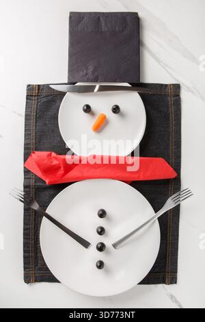 A beautiful Christmas or New Year's table setting featuring a snowman. Viewed from above, vertical. Stock Photo
