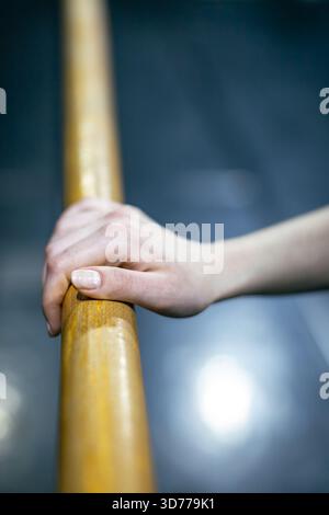 ballerina's hand resting on ballet barre Stock Photo