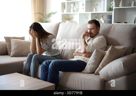 Sad couple complaining having relationship problems sitting on a couch at home Stock Photo