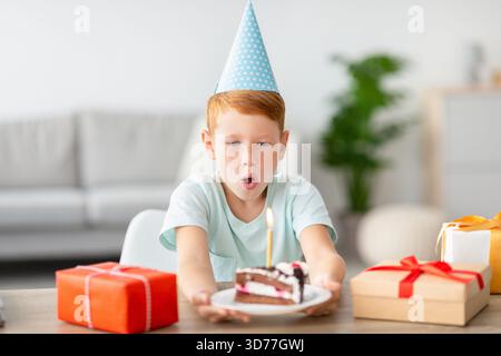 Cute Birthday Boy Celebrates by Blowing out Candles on Delicious Chocolate Cake at Home Stock Photo