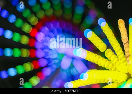Vivid spiral bokeh lights in rainbow tones, created from festival night motion, forming a dynamic abstract background for celebration creative design. Stock Photo