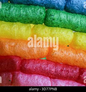 Macro rainbow texture made from colored corn puffs. A vibrant biodegradable background ideal for eco crafts, festival themes, and creative design use. Stock Photo