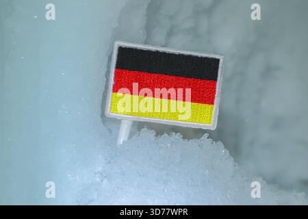 German flag patch set in glacial snow, reflecting Bavarian Alps and winter tourism. Strong conceptual fit for climate stories and national symbolism. Stock Photo