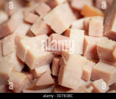 A close-up, high-angle view of a large pile of freshly cubed, pink, savory ham pieces, ready to be used as an ingredient in a cafe kitchen. Stock Photo