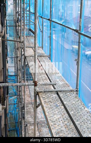Scaffolding structure providing temporary access with platforms and protective netting for a building renovation project Stock Photo