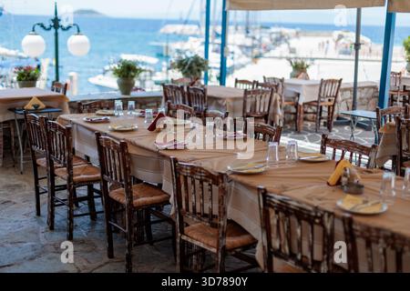 Long table set for dinner at a greek restaurant with an ocean view Stock Photo