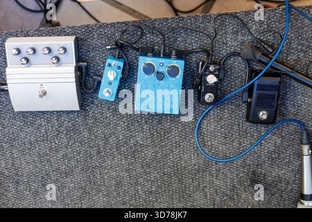 Various guitar effects pedals arranged on a performance stage floor Stock Photo
