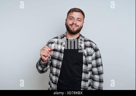 portrait of young man stands confidently with a subtle smile and a gesture, portraying intrigue on white background Stock Photo