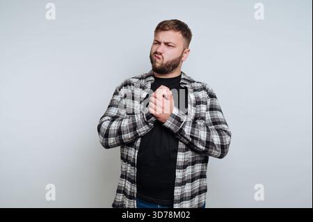 portrait of young man with a beard poses with a confident expression, wearing a plaid shirt on white background Stock Photo