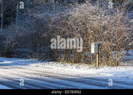 Outdoor mailbox placed along the street between neighboring residential houses. Metal post box used for daily postal delivery in a suburban area Stock Photo