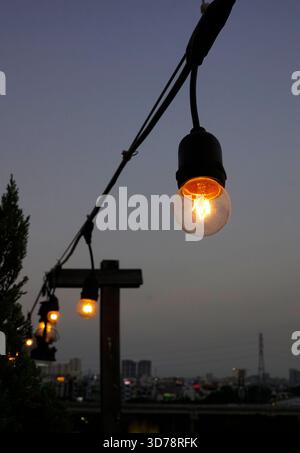 Classic light bulbs hanging around rooftop bar Stock Photo