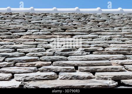 Close-up of a textured stone wall under a clear blue sky in a sunny setting Stock Photo