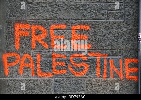 Orange graffiti reading “Free Palestine” painted on a textured stone wall in Edinburgh. Edinburgh,Scotland Stock Photo
