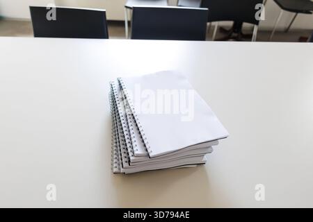 stack of blank spiral notebooks on a classroom table ready for student use during lessons Stock Photo