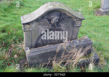 Old broken gravestone with carved decoration in a grassy Edinburgh cemetery.Edinburgh,Scotland Stock Photo
