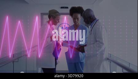 Discussing three medics in lab coats and scrubs, reviewing tablet in hospital hallway, magenta ECG Stock Photo