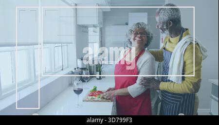 Chopping couple wearing red and striped aprons at counter, cutting board with tomatoes, copy space Stock Photo