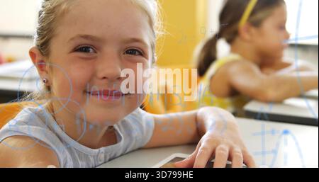 Smiling blonde student resting hand on tablet at classroom desk wearing blue top, math overlay Stock Photo