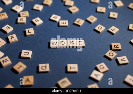 woke tiles creatively arranged to spell word woke against a blue background Stock Photo