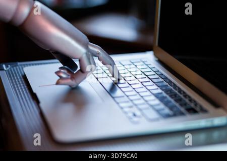 Robot hand interacting with laptop keyboard Stock Photo