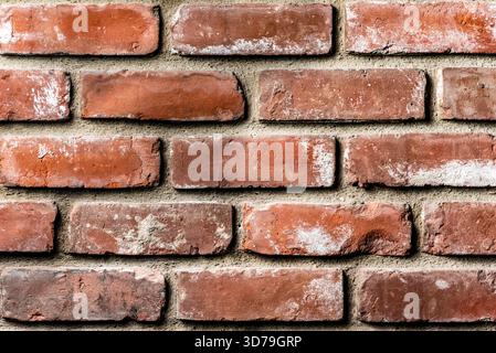 Close-up view of a weathered red brick wall showing rough texture and mortar joints. Patterned bricks create a rustic surface. Stock Photo