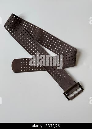 Brown leather belt with perforated design on white surface, suitable as fashion accessory background. Mobile photo Stock Photo
