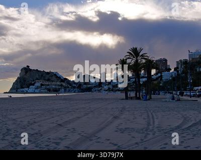 Evening sun sheds light on a beach that is lined with high-rise hotels and houses in popular tourist destination Benidorm, Spain Stock Photo