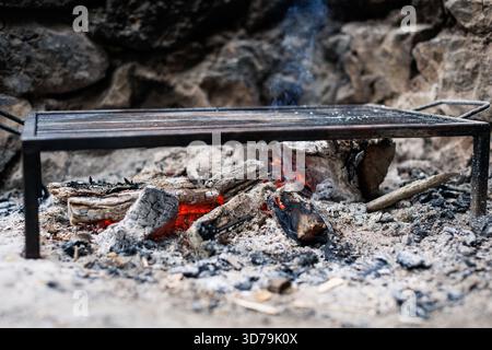 open fire with grill rack set on natural stones in a rustic outdoor setting Stock Photo
