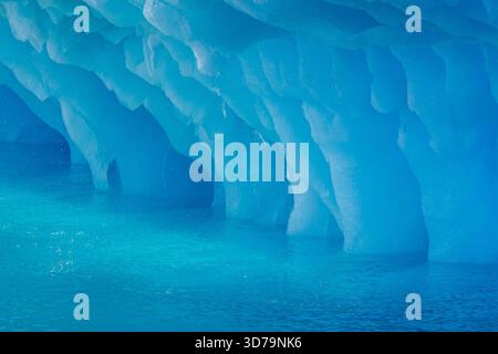 Dripping blue ice pattern from erosion by sea water on base of melting iceberg in the Arctic Ocean at Svalbard / Spitsbergen, Norway Stock Photo