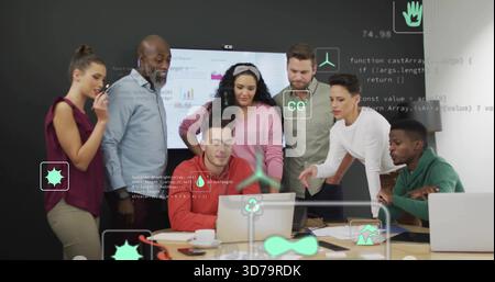 Collaborating team surrounding laptop user in meeting room, reviewing wall display with AR icons Stock Photo