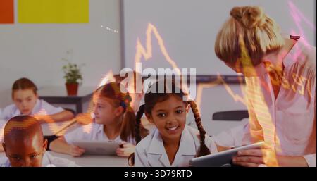Leaning teacher assisting girl in white shirt using tablet in primary class, with graph overlay Stock Photo