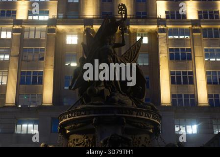 The Nelson Monument, Exchange Flags, Liverpool, at night. silhouetted against the brightly lit, modern Exchange Buildings façade. Stock Photo